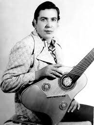 Retrato antiguo en blanco y negro del Maestro Elkin Pérez Álvarez joven, con chaqueta clara, pañuelo al cuello y su tiple