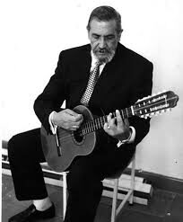 El Maestro Elkin Pérez Álvarez, de traje oscuro y corbata, sentado tocando el tiple (fotografía en blanco y negro)