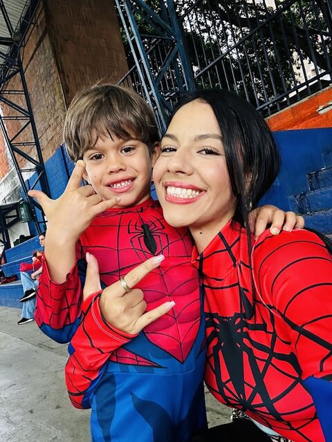 Docente y niño disfrazados de superhéroe araña sonriendo en una selfie, el niño haciendo un gesto con las manos