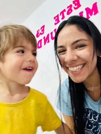 Docente sonriente en una selfie junto a un niño pequeño de camiseta amarilla que ríe