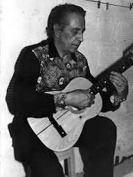 Fotografía en blanco y negro del Maestro Elkin Pérez Álvarez tocando guitarra, con camisa estampada